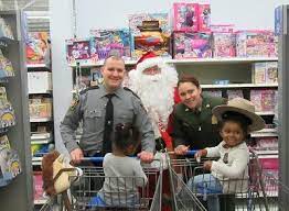 A man in a santa suit and two women with shopping carts