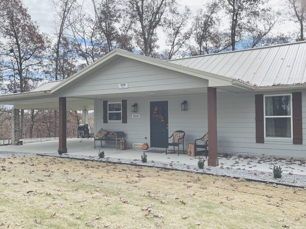 A house with a porch and two chairs in front of it.