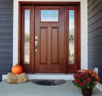 A front door with a pumpkin and flowers on the porch.