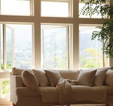 Cozy sofa by large sunlit windows.