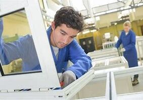 A man working on a window frame in a factory.